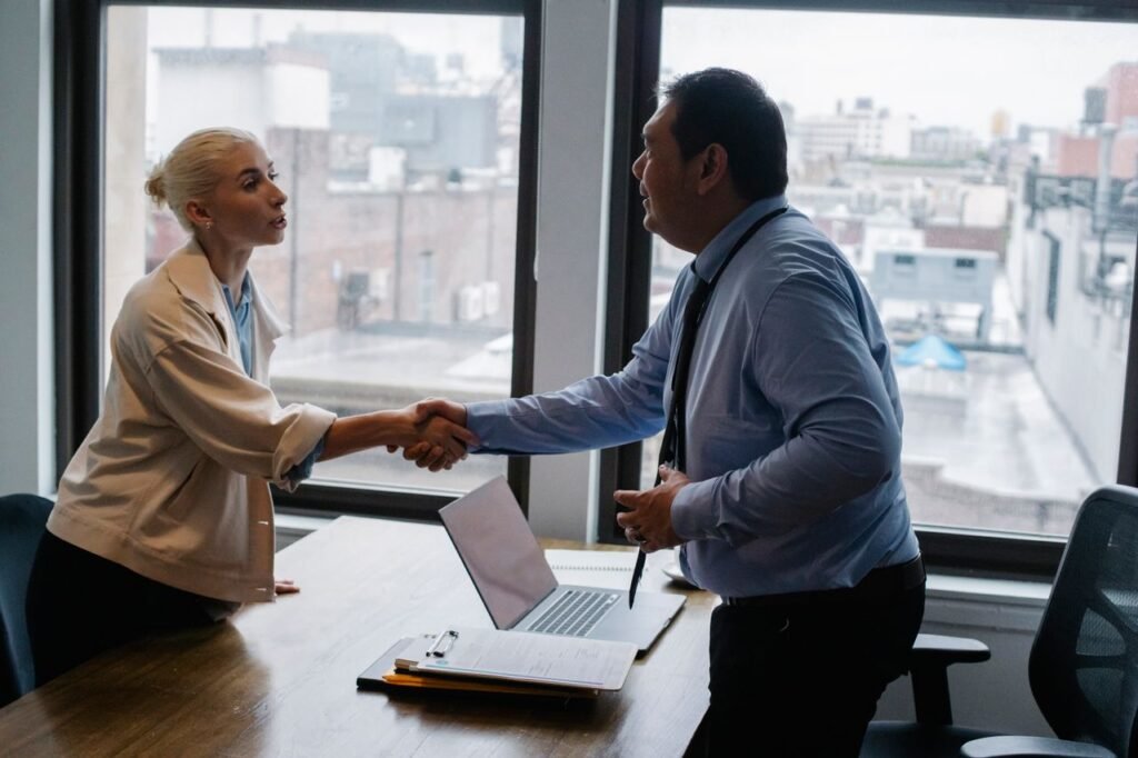 The Art of Drawing Readers In: Your attractive post title goes here Young female candidate shaking hands with employer before job interview in light office with urban landscape through windows